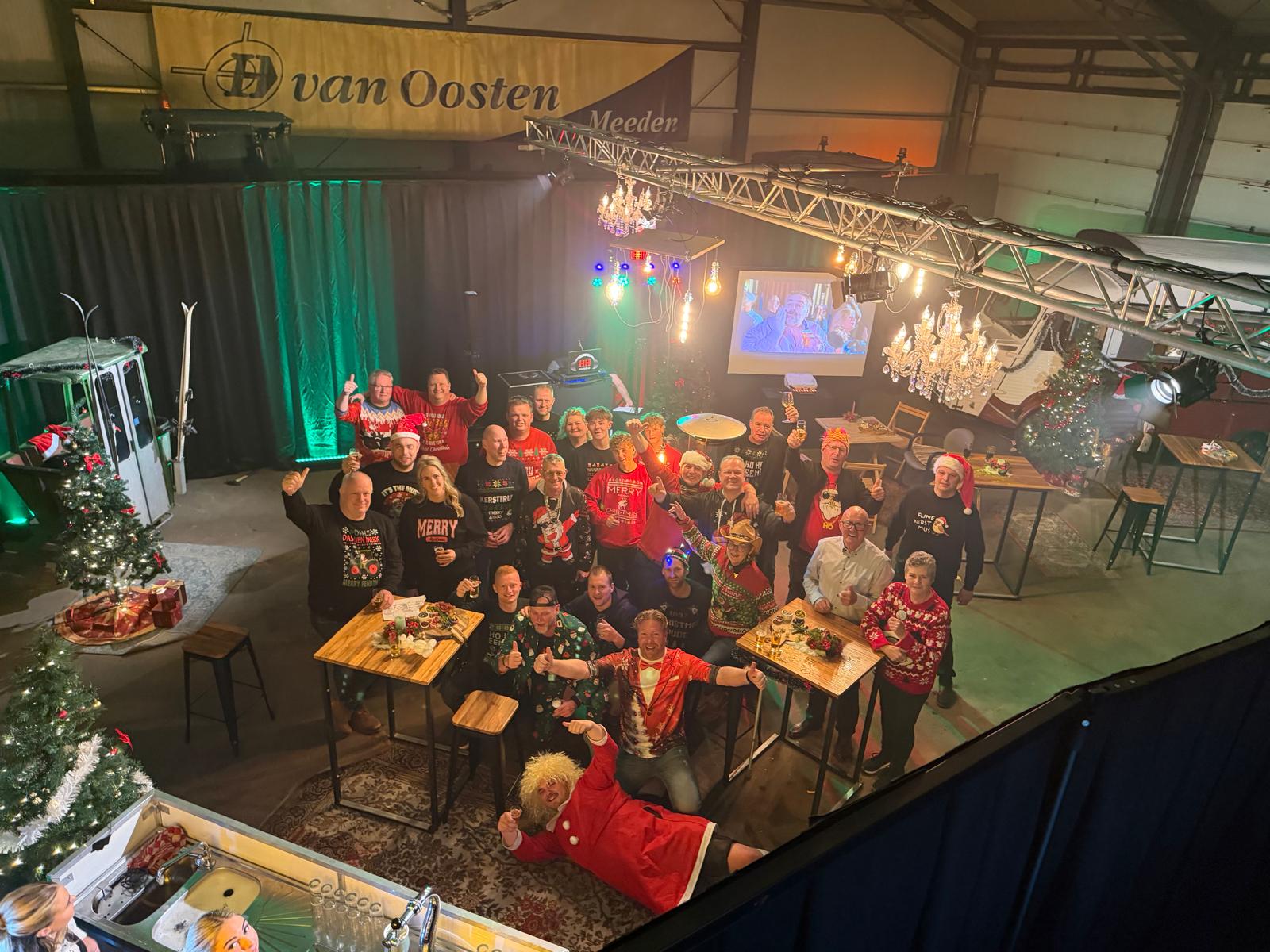 Groepsfoto van kerstfeest in feestelijk versierde bedrijfshal