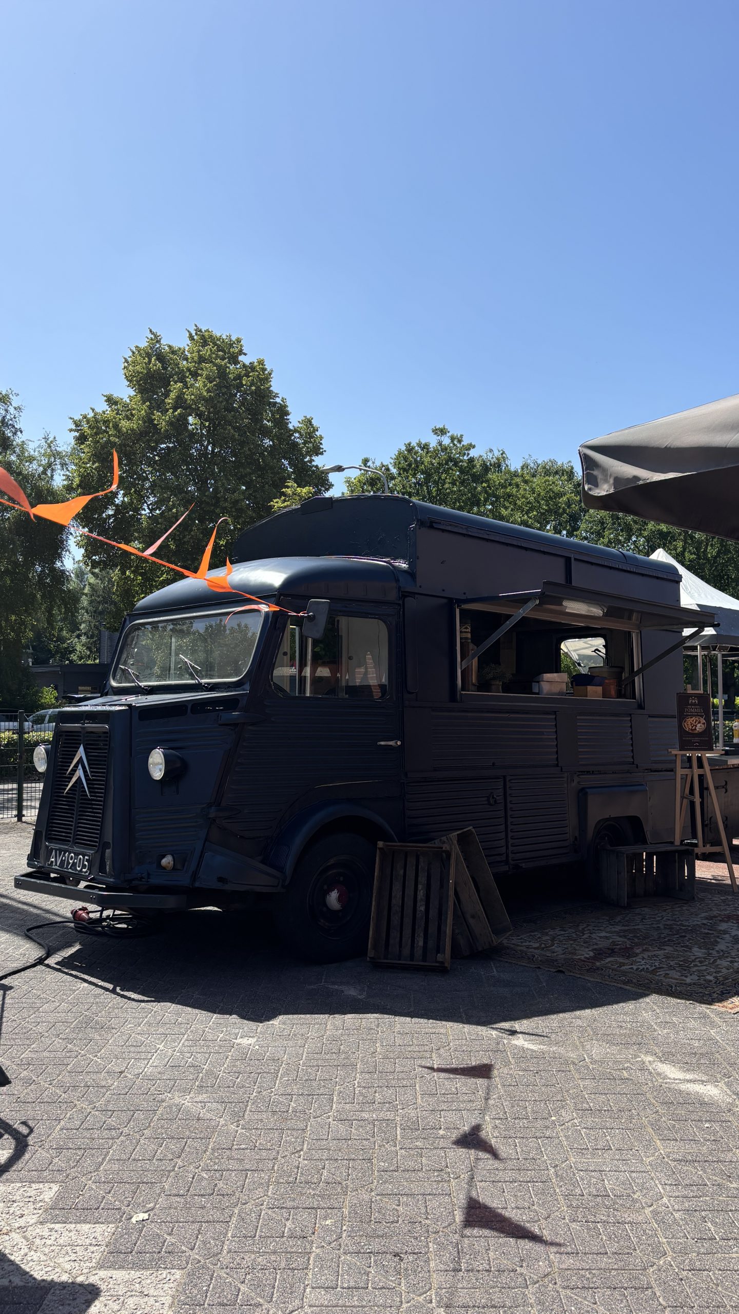 Zwarte vintage Citroën foodtruck op een zonnig buitenplein.