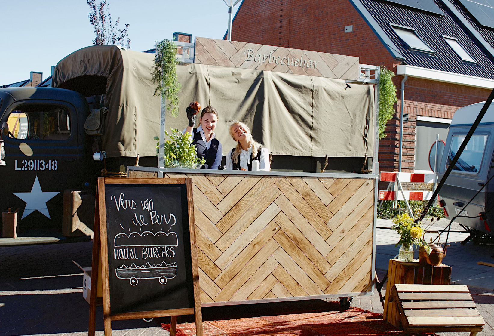 Twee lachende vrouwen achter een houten Barbecuebar foodtruck.