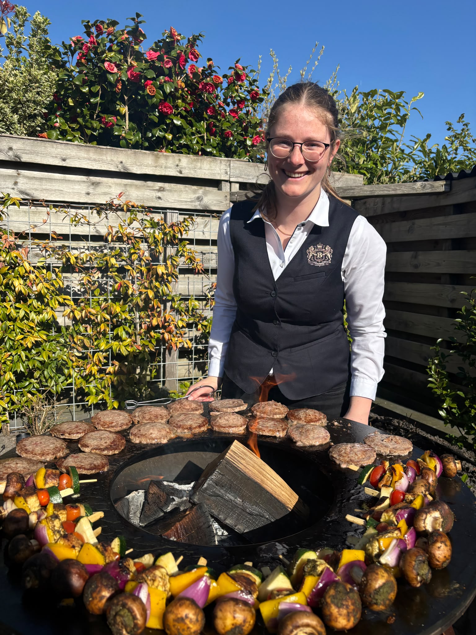 Vrouw grilt hamburgers in zonnige tuin