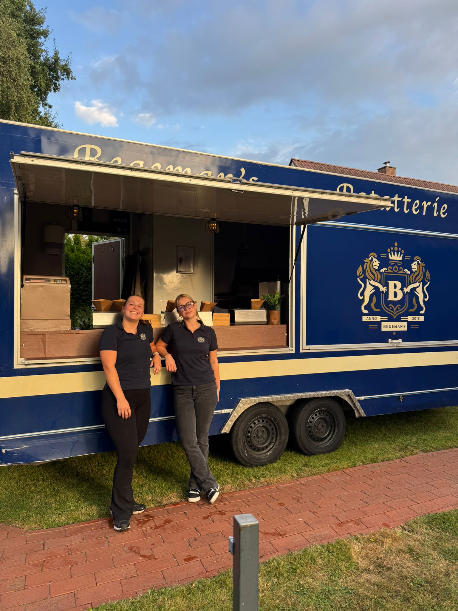 Twee lachende vrouwen voor een blauwe Begeman