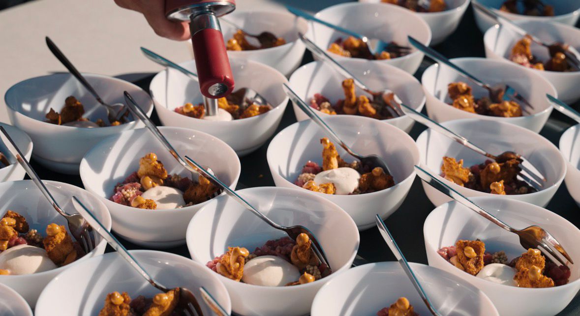 Kok vult dessertkommen met saus op een buffet