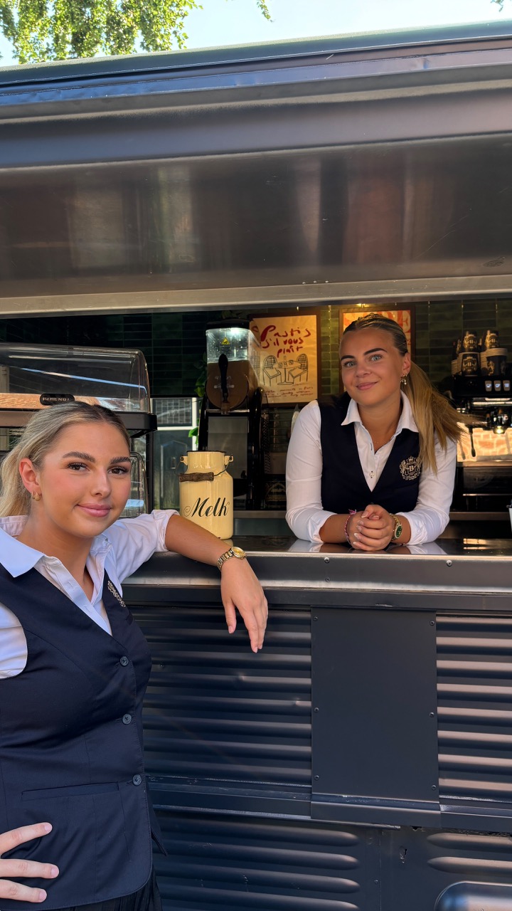 Twee serveersters bij de uitgiftebalie van een koffiebar